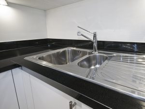 stainless steel kitchen sink detail on black granite worktop