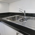 stainless steel kitchen sink detail on black granite worktop
